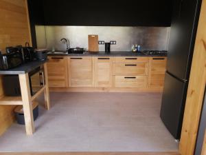 布拉伊NIAOULI LODGE的厨房配有木制橱柜和黑色冰箱。