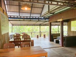 邦隆Backpacker Hostel and Jungle Trekking的一间带木桌和椅子的餐厅以及一个阳台