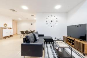 迪拜Moonlight Hostel JBR的客厅配有沙发和墙上的时钟