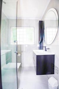 约翰内斯堡2 Bedroom Sandton Apartment的带淋浴、盥洗盆和镜子的浴室