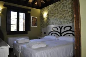CampomanesHotel Rural El Reundu的一间卧室设有两张带白色床单的床和窗户。