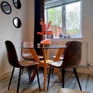 格洛斯特2 Bedroom House in Quiet Area, Close to M5 With Free Parking by Glos Homes Ltd的餐桌、椅子和花瓶