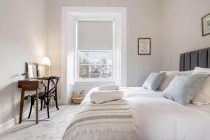 圣安德鲁斯Skye Sands - 11 Alexandra Penthouse - St Andrews的白色的卧室设有床、书桌和窗户