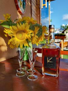 MirnaVineyard Cottage Sončni grič的一瓶威士忌和两杯带鲜花的桌子
