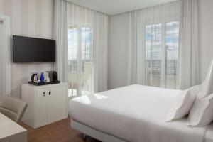 马德里马德里阿托查NH酒店的一间白色卧室,配有一张大床和一台电视