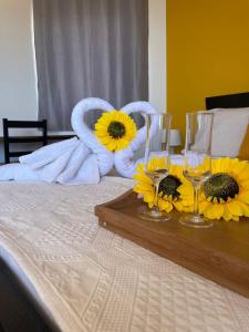 蓬塔杜索尔Residencial Sol Point Art的床上的桌子上摆放着向日葵和酒杯