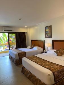 长滩岛Paradise Garden Hotel and Convention Boracay Powered by ASTON的酒店客房设有两张床和一个阳台。