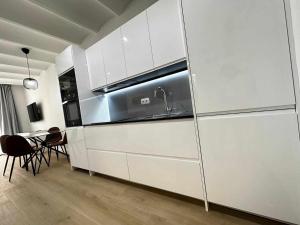 比纳罗斯A H Rentals Picasso apartamento的厨房配有白色橱柜、水槽和桌子