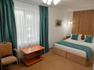 乌拉尔斯克Kurmet Hotel的配有一张床和一把椅子的酒店客房