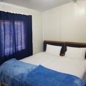 哈塔伊GÜN IŞIĞI KONAKLAMA的一间卧室配有两张床和蓝色窗帘