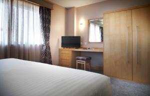 诺斯利The Suites Hotel & Spa Knowsley - Liverpool by Compass Hospitality的一间卧室配有一张床和一张带镜子的书桌