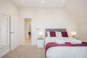 SurbitonRoomspace Serviced Apartments Newlands House的白色卧室配有一张带红色枕头的大床