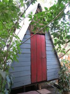 邦隆Ratanakiri Homestay & Jungle Trek的绿树成荫的蓝色房子上的红门