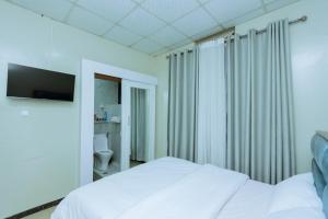 基加利Ibi Villa Retreat的卧室配有白色的床和电视。