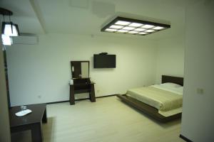 塔拉兹SEQUOIA boutique hotel的卧室配有一张床,墙上配有电视。