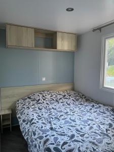 滨海苏拉克Mobil-home 177的一间卧室配有一张带蓝白色毯子的床