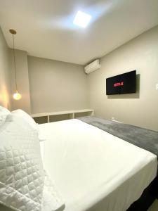 阿拉亚尔-杜卡布Casa Amora的卧室配有白色的床和墙上的电视。