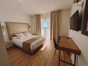 林孔-德拉维多利亚Fay Victoria Beach的配有一张床、一张书桌和一扇窗户的酒店客房