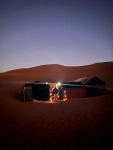 AdrouineGambe Camp的坐在沙漠帐篷里的人