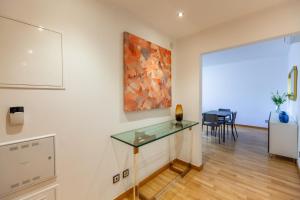 里斯本Apartamento Lisboa Sete Rios的一间设有玻璃桌和墙上绘画的房间