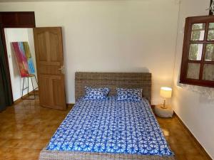 GourbeyreZayann Zen的一间卧室配有一张带蓝色床单和一盏灯的床。