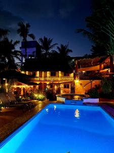 埃斯孔迪多港Hotelito Swiss Oasis -Solo Adultos - Adults only的一座游泳池,在晚上在建筑物前