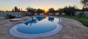 莱夫基米ANEMOMYLOS Lefkimmi LUXUS SUITES-BOUTIQUE HOTEL & POOL的庭院内的游泳池,背景是日落