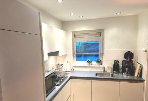 比伦Helmpol的厨房配有白色橱柜、水槽和窗户。