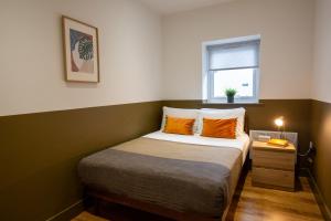 兰鲁斯特RWST Holiday Lodges的一间卧室配有带橙色枕头的床和窗户。