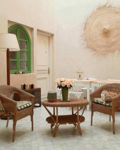 马拉喀什Riad Nour, Maison de charme.的客厅配有两把椅子和一张鲜花桌