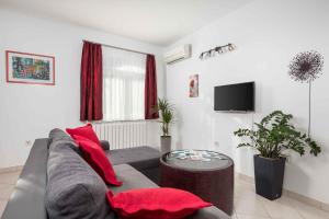克拉列维察Two-Bedroom Apartment in Kraljevica II的客厅配有灰色沙发和红色枕头