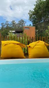 San Mamede de CarnotaNidos de carnota的两个黄色枕头坐在游泳池旁