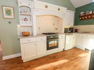南特威奇Molls Cottage的厨房配有白色橱柜和烤箱。