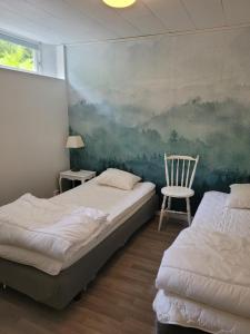 KulltorpBokskogens Guesthouse的两张位于带椅子和绘画的房间内的床