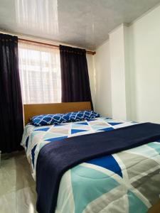波哥大Apartaestudio cerca al Aeropuerto的一间卧室配有一张带蓝白色毯子的床