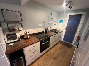 卡纳芬Cosy North Wales 2 BEDROOM Chalet的厨房配有白色橱柜和木制台面