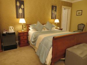特拉利溪流庄园酒店的一间卧室配有一张大床、两盏灯和一把椅子