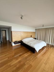 埃斯特角城Penthouse Villa brava的卧室内的一张大床,铺有木地板