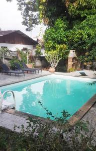 MatouryCharmant Lodge tout confort的庭院内的游泳池,带椅子和树木