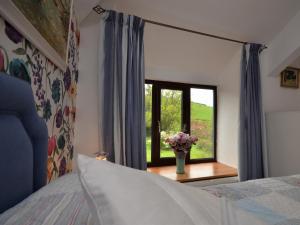 Ugborough2 Bed in Bigbury-on-Sea KEMTH的一间卧室设有一张床和一个花瓶的窗户