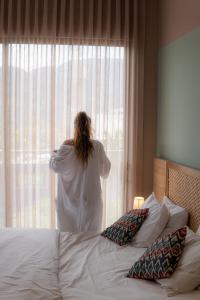 伊瓦格FR Hotel的一位女士,看着酒店房间的窗户