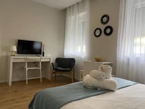 里斯本Charming Studio Apartment in Campolide - 2F的一间卧室配有一张床、一张书桌和一台电视