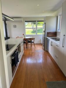 罗托鲁瓦Rotorua Lakes House的厨房铺有木地板,配有白色橱柜。