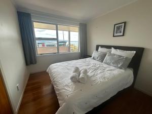 罗托鲁瓦Rotorua Lakes House的一间卧室配有一张带白色床单的床和一扇窗户。