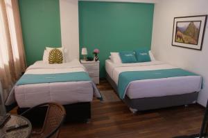 库斯科MATARA GREENS HOTEL的配有两张床铺的蓝色和绿色墙壁客房