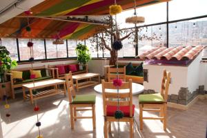 库斯科MATARA GREENS HOTEL的餐厅设有桌椅和窗户。