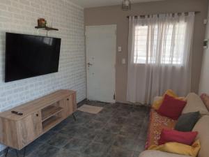 内乌肯La Casita de Nala的一间客厅,在砖墙上配有平面电视