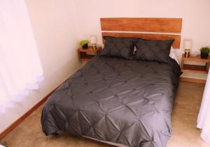 基多Cabaña en la montaña Ilalo - Quito的卧室配有带灰色棉被的床
