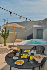 皮尔戈斯露娜圣托里尼套房旅馆的一个带游泳池的庭院里一张桌子,上面摆放着食物和饮料