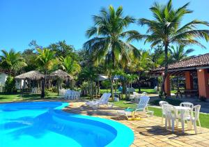 瓜拉派瑞Acquamarine Park Hotel的度假村设有游泳池,游泳池内摆放着白色椅子和棕榈树